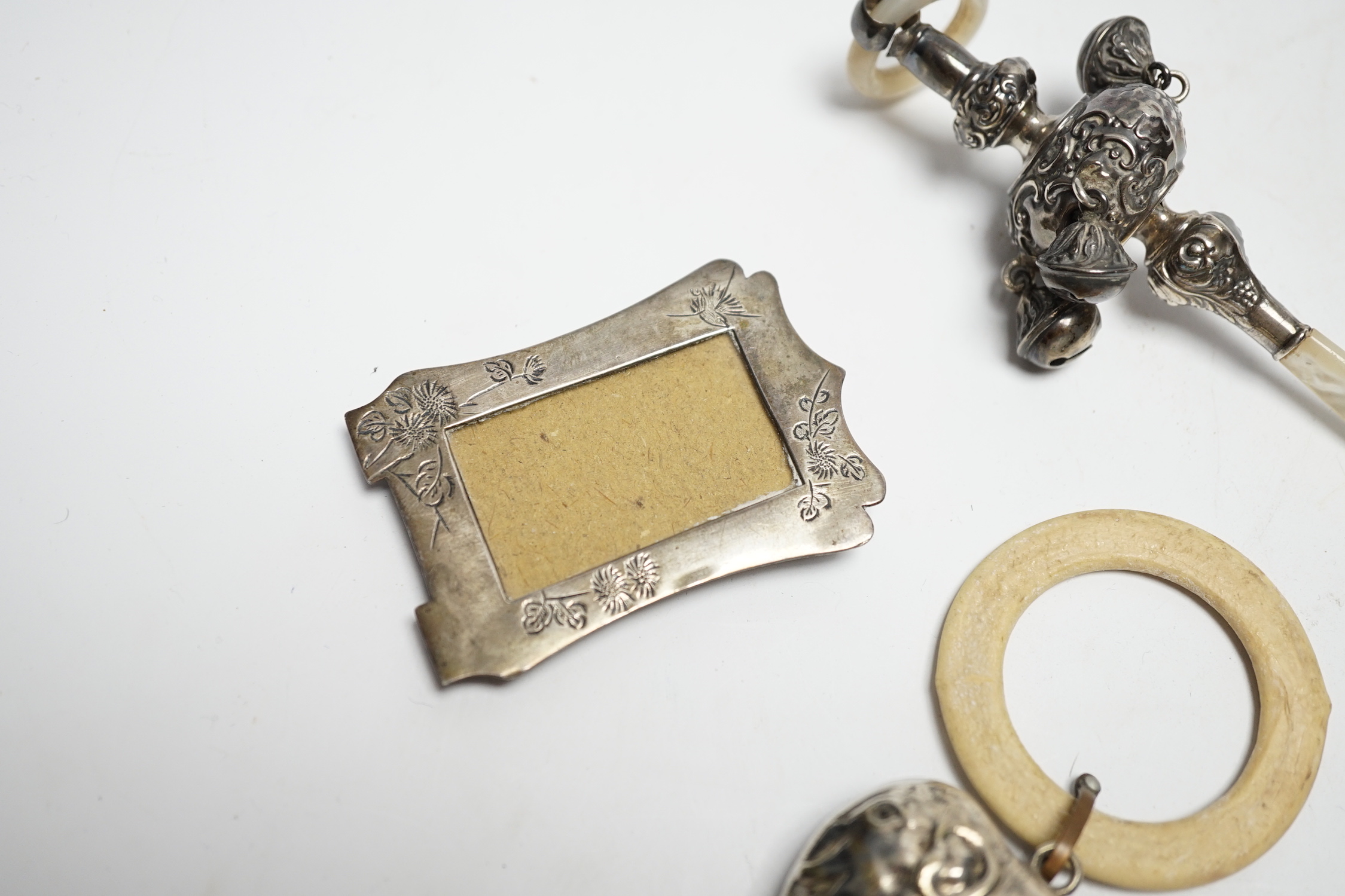 An Edwardian silver and mother of pearl child's rattle, 11cm, together with a miniature white metal photograph frame and a plated child's rattle.